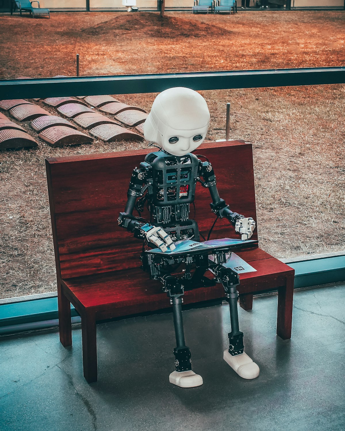 A humanoid robot sitting on a bench with a tablet — basically Jarvis on his day off